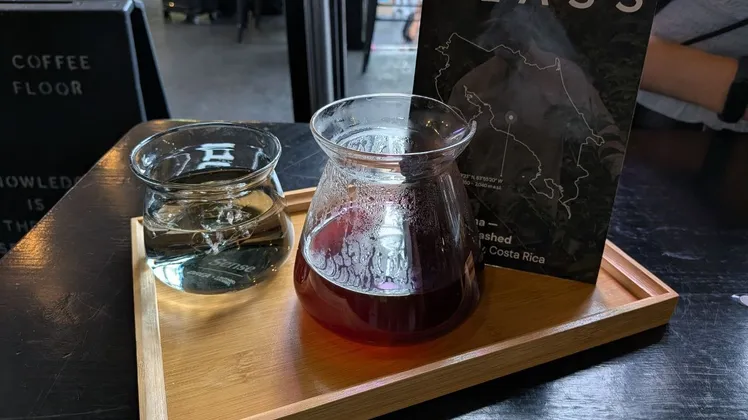 A Gesha filter coffee served in a glass carafe on a wooden tray at Glass Coffee in Camden Town